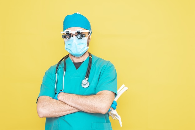 Jonge dokterschirurg gekleed in groen op gele achtergrond