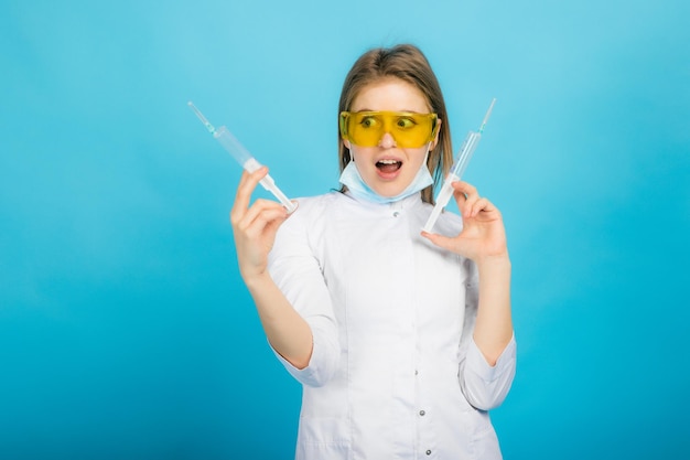 Jonge doktersvrouw met spuit en gele bril