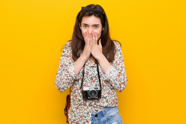 Jonge donkerbruine reizigersvrouw die over iets lachen, die mond behandelen met handen