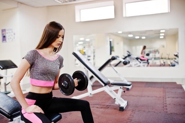 Jonge donkerbruine sexy slanke vrouw die training doet bij gymnastiek.