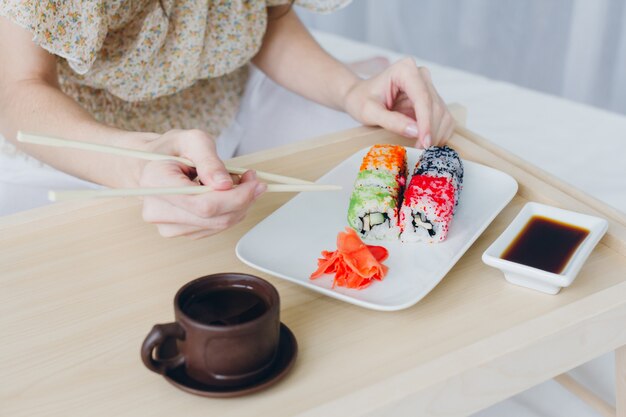 Jonge donkerbruine vrouw die sushi eet