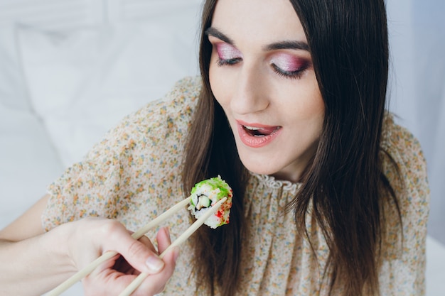 Jonge donkerbruine vrouw die sushi eet
