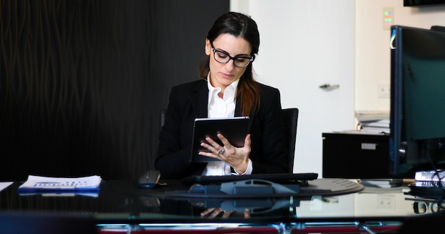 Jonge doordachte secretaris met behulp van een digitale tablet op haar bureau