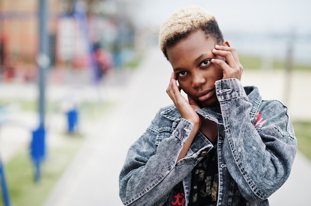 Jonge duizendjarige Afro-Amerikaanse meisje in de stad. Gelukkig zwarte vrouw met draadloze koptelefoon. Generatie Z-concept.