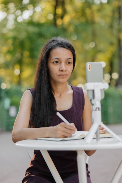 Jonge duizendjarige afro-amerikaanse vrouw kijkt naar een webinar of livestream vanaf haar smartphone en