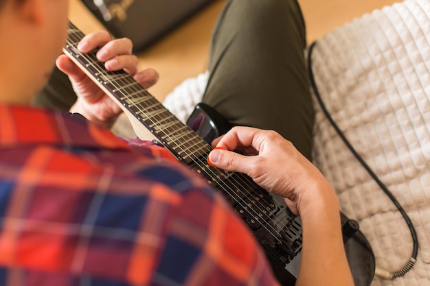 Jonge duizendjarige man die elektrische gitaar speelt blijf thuis thuis activiteit leerlessen