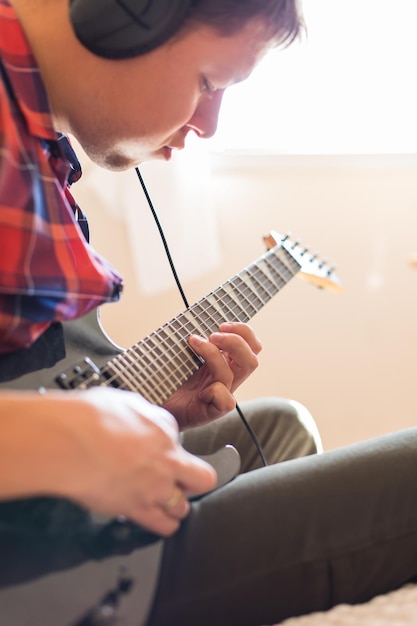 Jonge duizendjarige man die elektrische gitaar speelt Blijf thuis thuis activiteit leerlessen