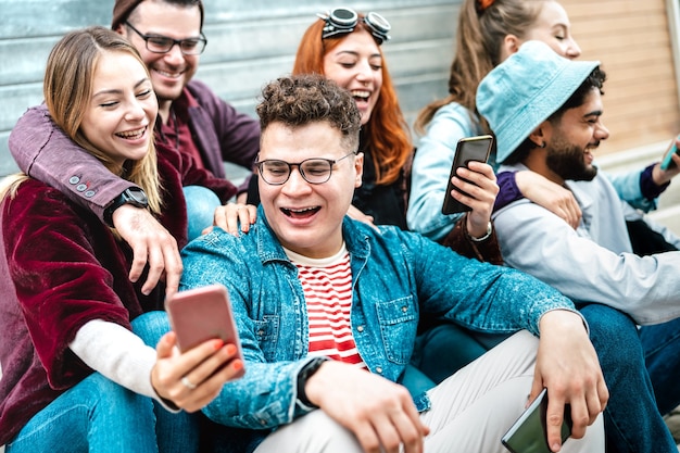 Jonge duizendjarige vrienden die plezier hebben met mobiele telefoon op de campus van de universiteitswerf - Vrolijke mannen en vrouwen die samen tijd doorbrengen met het kijken naar grappige virale smartphonevideo - Helder filter met focus op de centrale man