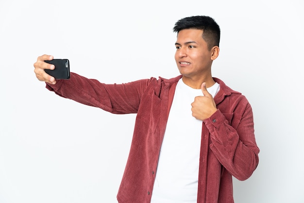 Jonge Ecuadoriaanse man geïsoleerd op een witte muur maken een selfie met mobiele telefoon