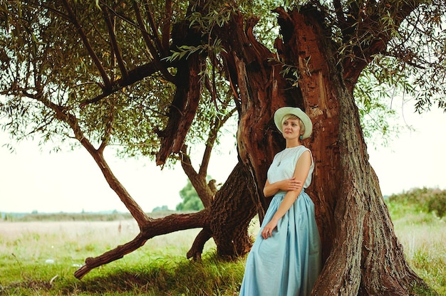 Jonge elegante gelukkige vrouw in witte hoed in het veld wandelen, glimlachend. Vintage kleding. Herfstseizoen