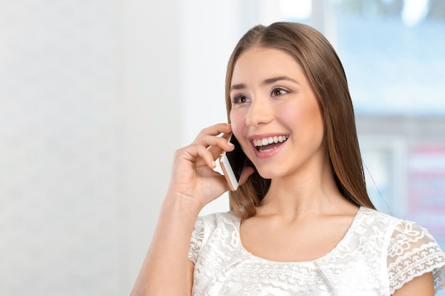 Jonge elegante vrouw die op mobiele telefoon spreekt