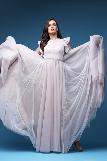 Jonge elegante vrouw in lange roze jurk. elegante vliegende stof, avond, trouwjurk.