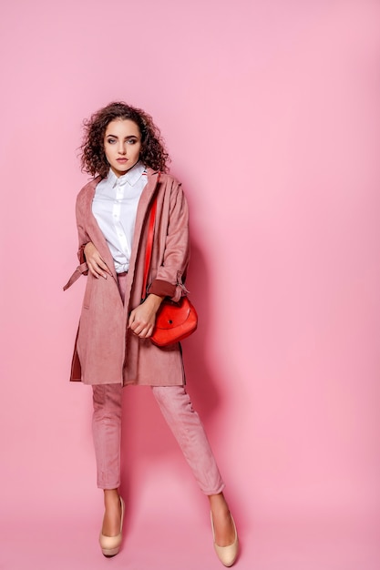 Jonge elegante vrouw in trendy roze jas