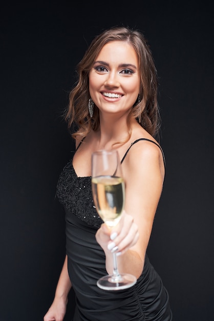 Jonge elegante vrouw met glas champagne op feestje.