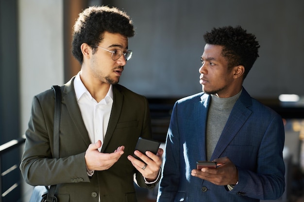 Foto jonge elegante zwarte man die luistert naar commentaar van multi-etnische collega