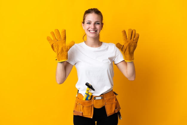 Jonge elektricienvrouw die op gele muur wordt geïsoleerd die tien met vingers telt