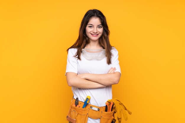 Jonge elektricienvrouw over bij het gele muur lachen