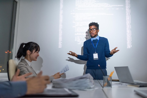 Jonge emotionele it-engineer van Afrikaanse etniciteit die voor het publiek staat tijdens het seminar en een van de presentatiepunten uitlegt