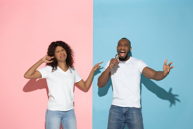 Foto jonge emotionele man en vrouw op roze en blauwe achtergrond