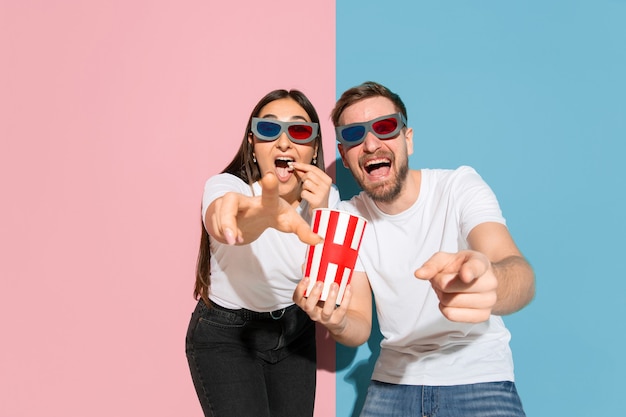 Jonge emotionele man en vrouw op roze en blauwe muur