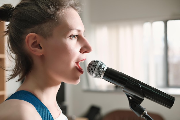 Foto jonge emotionele vrouw die in een microfoon zingt vrouwelijke rockzangeres op een repetitie in een platenstudio