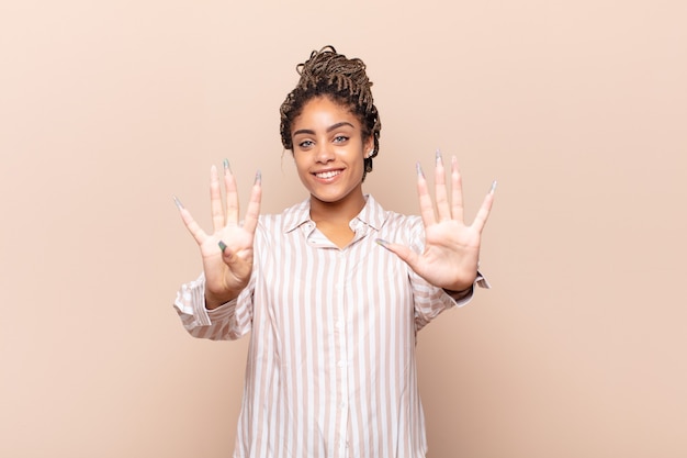 Jonge en afrovrouw die vriendelijk glimlacht kijkt, nummer negen of negende met vooruit hand toont, aftellend