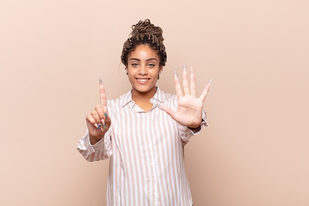 Jonge en afrovrouw die vriendelijk glimlacht kijkt, nummer zes of zesde met vooruit hand toont