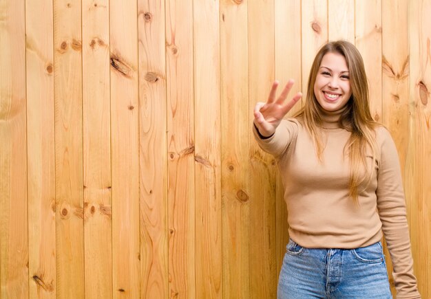 Jonge en blondevrouw die vriendelijk glimlachen kijken, nummer drie of derde met vooruit hand tonen, die aftelt