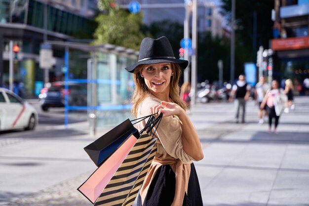 Foto jonge en elegante vrouw met over de schouder winkelzakken op een perfecte winkeldag