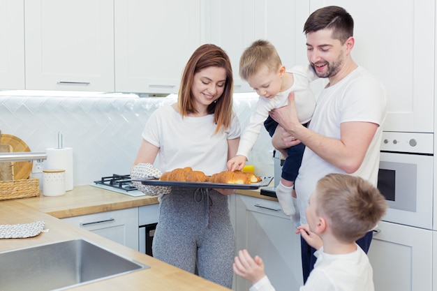 Jonge en gelukkige familie met twee jonge zonen die ontbijt samen in hun keuken voorbereiden