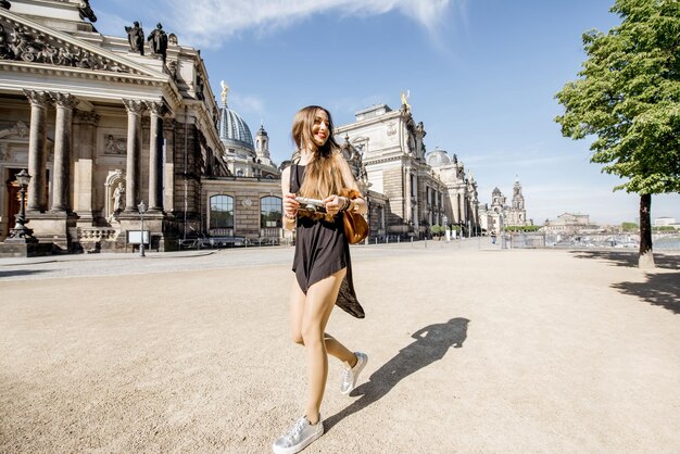 Jonge en gelukkige vrouw die het meest voor het oude universiteitsgebouw in Dresden, Duitsland loopt