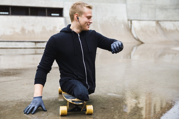 Jonge en gemotiveerde gehandicapte man met een longboard in het skatepark