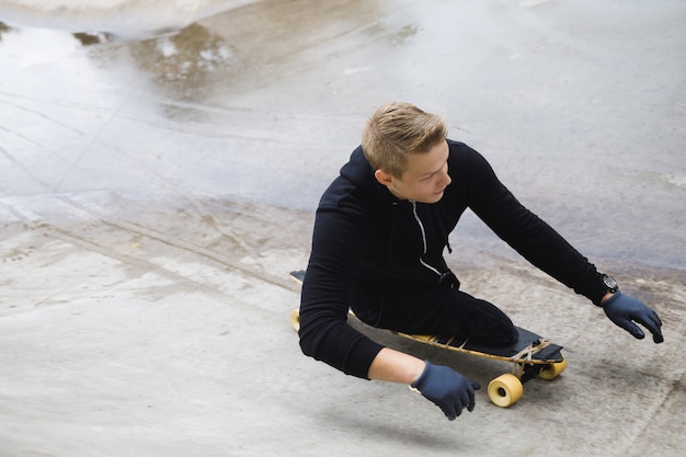 Jonge en gemotiveerde gehandicapte man met een longboard in het skatepark