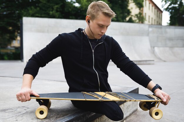 Jonge en gemotiveerde gehandicapte man met een longboard in het skatepark