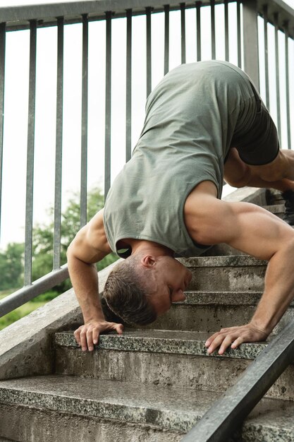 Jonge en gespierde man doet push-ups tijdens gymnastiektraining op straat