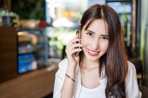 Jonge en mooie Aziatische freelance zakenvrouw met behulp van een slimme telefoon in het restaurant