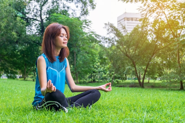 Jonge en mooie Aziatische vrouw het praktizeren yoga in openlucht in park met groene aardbackgro