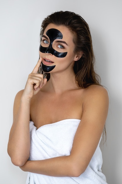 Foto jonge en mooie vrouw met zwarte peel-off masker op haar gezicht