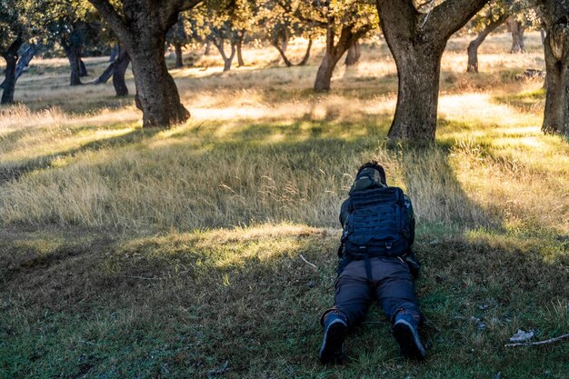 Jonge en onherkenbare jongen ligt en verstopt zich om foto's van de herten te maken