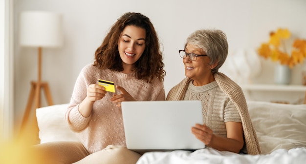 Jonge en oudere vrouwen gebruiken laptops voor online winkelen Dochter helpt moeder thuis