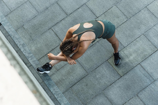 Jonge en sportieve vrouw rekt zich uit tijdens fitnesstraining buitenshuis