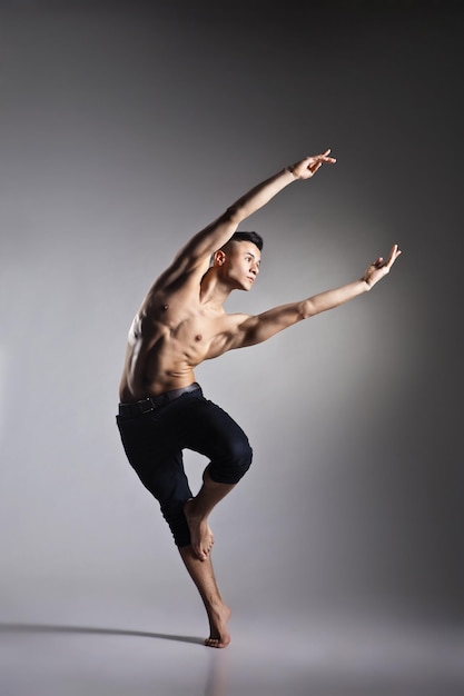 Jonge en stijlvolle moderne balletdanser op grijze achtergrond