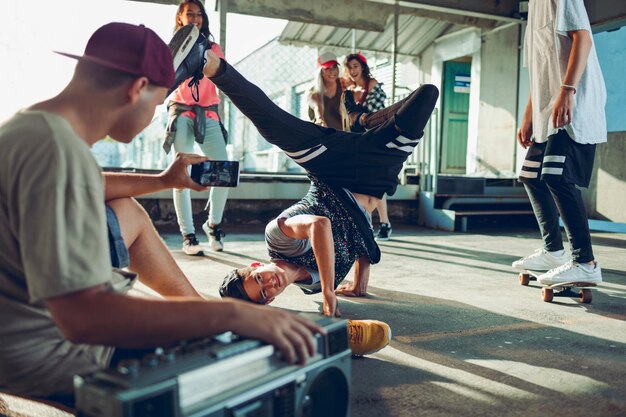 Jonge en uiteenlopende groep mensen die breakdancen en filmen op een smartphone op een parkeerplaats