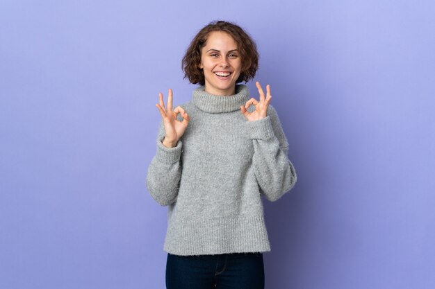 Jonge Engelse die vrouw op purpere muur wordt geïsoleerd die ok teken met twee handen toont