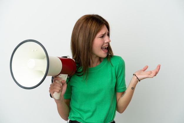 Jonge Engelse die vrouw op witte achtergrond wordt geïsoleerd die een megafoon houdt en met verrassingsgelaatsuitdrukking