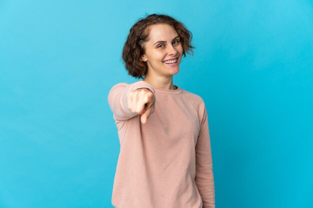 Jonge Engelse vrouw die op blauwe achtergrond wordt geïsoleerd die voorzijde met gelukkige uitdrukking richt