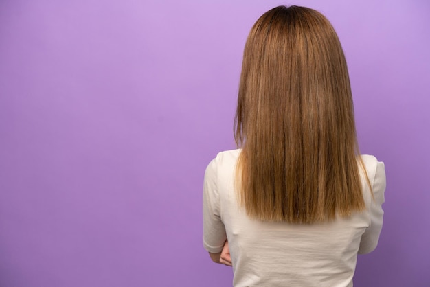 Jonge Engelse vrouw die op purpere achtergrond in rugpositie wordt geïsoleerd