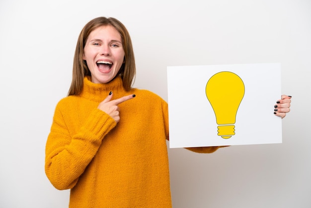 Jonge Engelse vrouw die op witte achtergrond een plakkaat met bolpictogram houdt en het richt