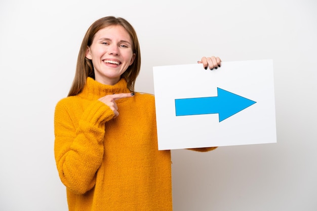 Jonge Engelse vrouw die op witte achtergrond wordt geïsoleerd die een plakkaat met pijlsymbool houdt en it