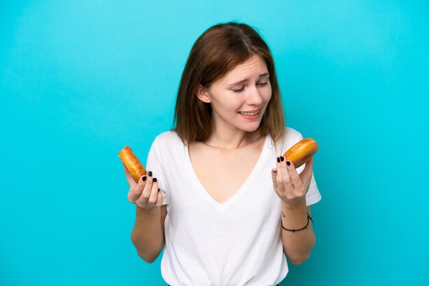 Jonge Engelse vrouw geïsoleerd op blauwe achtergrond met donuts met gelukkige uitdrukking